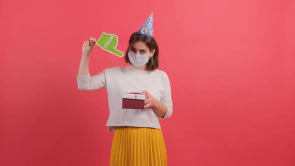 Woman with Medical Mask on Face Showing with a Cardboard Finger at the Gift Box. alt