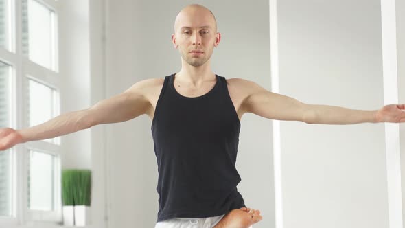 Young Flexible Male Training Doing Complex Yoga Exercises in Studio
