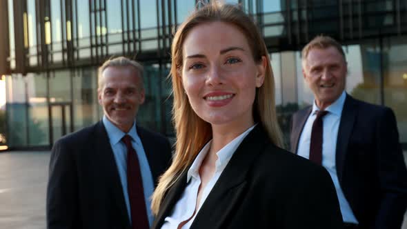 Confident Business Woman in Front and the Team in Background. Business Building Exterior