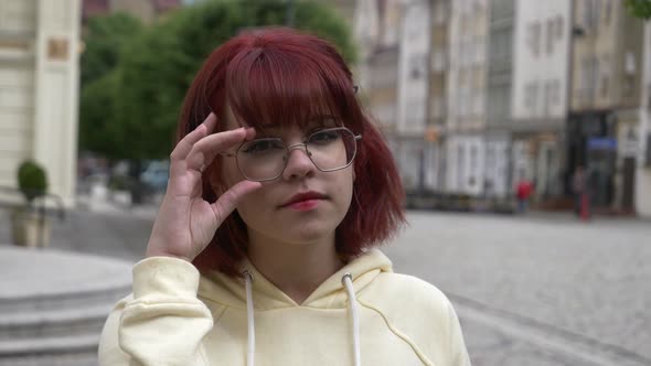 Young redhead ukrainian teen girl in glasses on city street