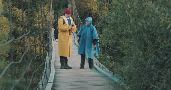 Man and Woman is Hiking are Walking on Suspension Bridge Look at Route on Gadget