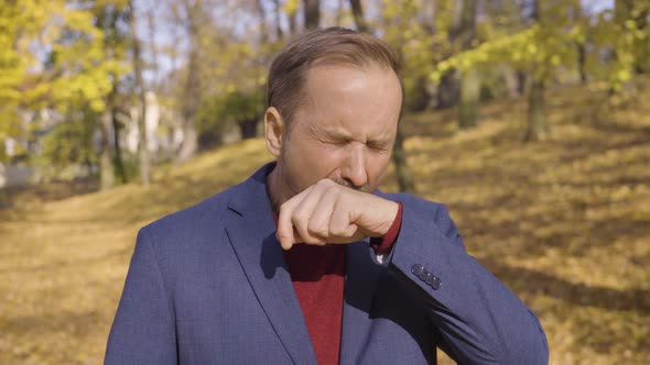 A Middleaged Handsome Caucasian Man Yawns and Acts Tired in a Park in Fall  Closeup