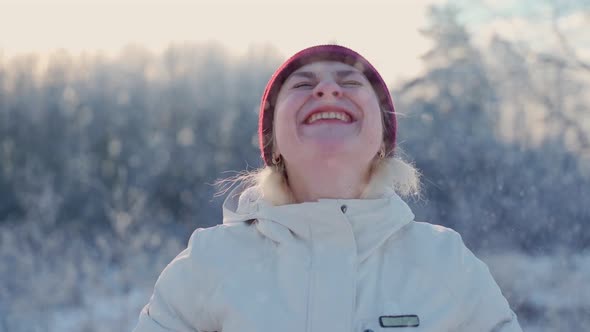 Portrait female blowing snowflakes holding in hands at winter outdoors alt