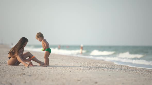 Older Sister Playing with Younger Brother Aground Near the Shore on Summer Vacation alt