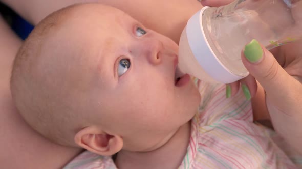 Mom Giving Baby To Drink Water From the Bottle alt