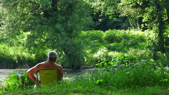 An elderly fisherman while fishing in the colorful summer shore.