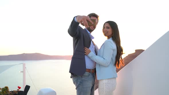 Couple Posing for Selfi Pictures at Sunset on Santorini