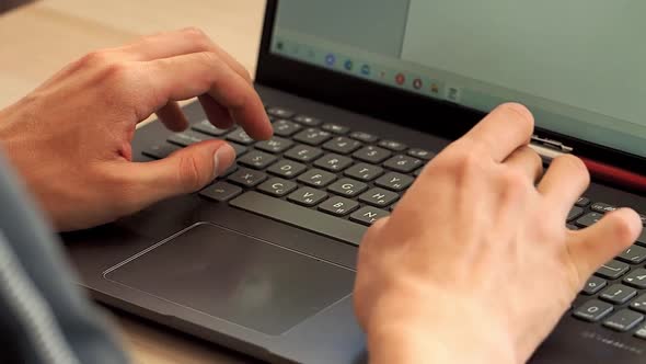 A Person Works on a Laptop Typing Text on a