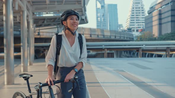 Asian businesswoman go to work at office walk and smile wear backpack look around take bicycle.