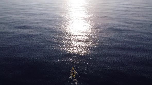 Fisherman trolling in kayak at mediterranean sea aerial drone view during sunrise. alt