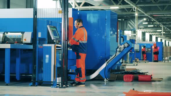 Factory Worker Operating an Industrial Machine on a Modern Assembly Line alt