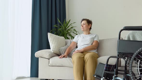 Portrait of Mature Woman with Wheelchair Looking at Camera in Living Room alt