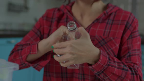 Female Hands Compressing Plastic Bottle While Sorting Recyclable Waste at Home alt