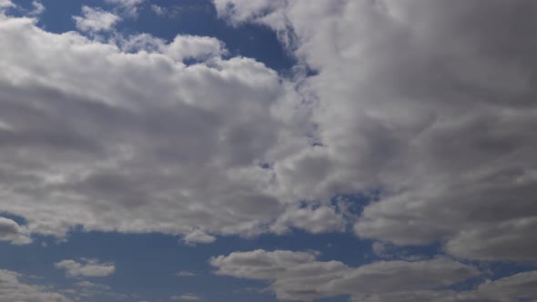 Time lapse: the sun hidden behind fluffy clouds flying in the sky.