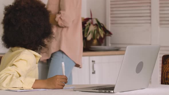 Little Focused Afro American Schoolgirl Studying Remote Online From Home Using Laptop alt