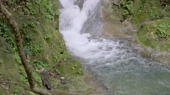 Slow Pan Up Fast Streamed Water Fall With Mossy Rocks And Plants Laying Aside alt