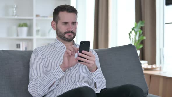 Serious Young Businessman Using Smartphone at Home alt
