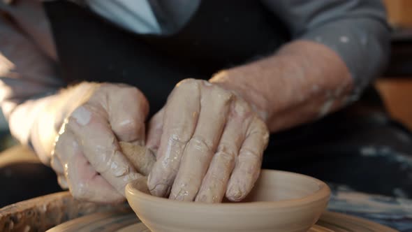 Close-up of Old Master's Hands Making Beautiful Bowl on Spinning Wheel in Workshop alt