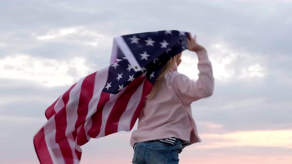 Back View Blonde Girl Waving National USA Flag Outdoors Over Sunset Sky at Summer on Beach American alt