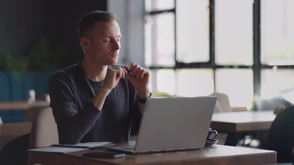 Thoughtful Serious Young Man Student Writer Sit at Home Office Desk with Laptop Thinking of alt