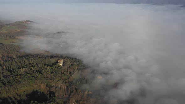 Aerial view of a palace and fog in the forest in Umbria, Italy