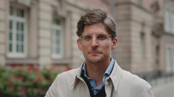 Middle Aged Man Putting on Eyeglasses and Looking at Camera alt