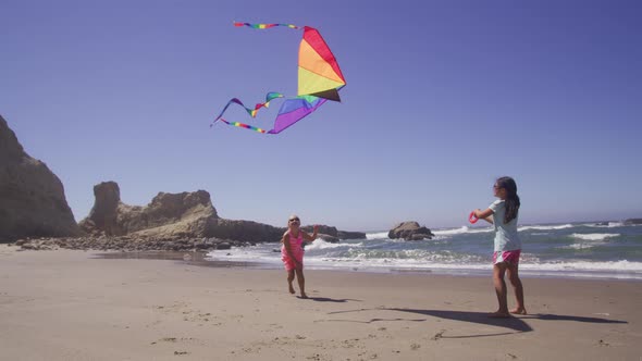 Two young girls flying kite at beach