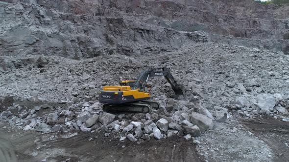 Volvo Excavator Rakes Stones in a Granite Quarry