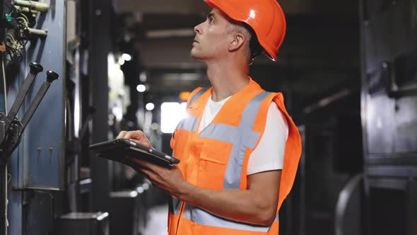 Professional Male Heavy Industry Engineer Wearing Safety Uniform and Using Tablet Computer
