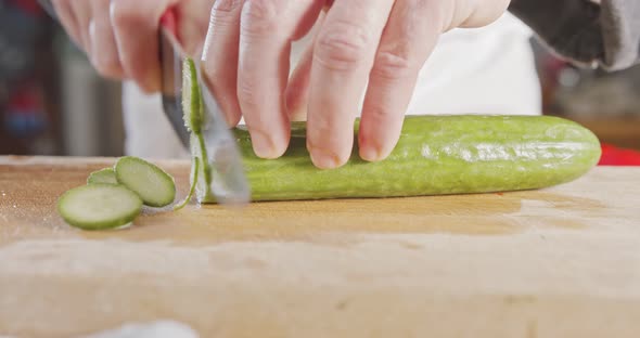Slow motion close up of a chef knife slicing a cucumber alt