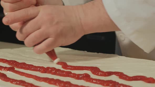 Man Pastry Chef Squeezes the Jam of Berries Onto a Cake To Be Baked