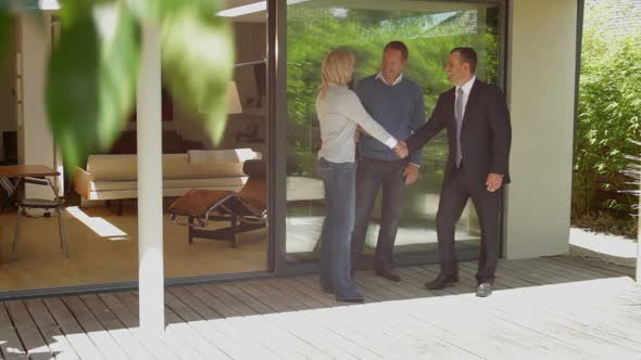 Wide, Tracking Left shot portrait of couple with estate agent in front of house alt
