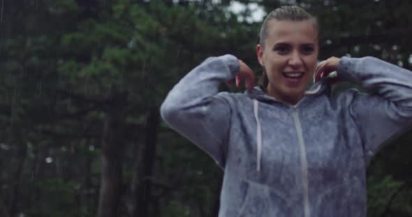 A Young Woman Takes Off Her Hood Resting After Running on a Rainy Day alt