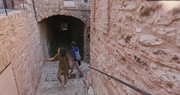 Four Happy Tourist People Walking and Running Amazed Through Small Street Visiting Rural Town of alt