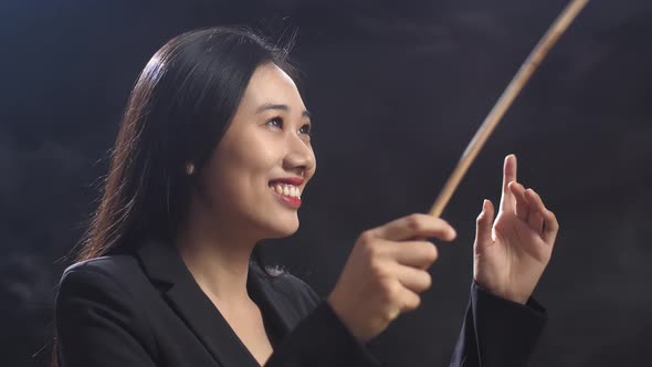 Close Up Of Asian Conductor Woman Holding A Baton And Showing Gesture Quickly In The Black Studio alt