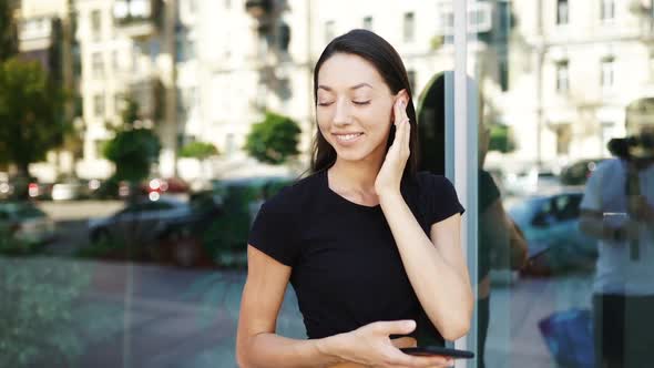 Portrait of a Young Brunette Woman with Headphones While Walking alt