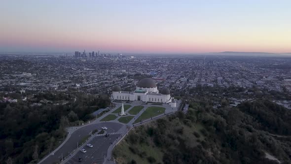 Aerial orbit of Griffith Observatory and Los Angeles city skyline seen in the distance. alt