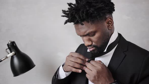 African American Businessman in Suit Putting on Tie alt