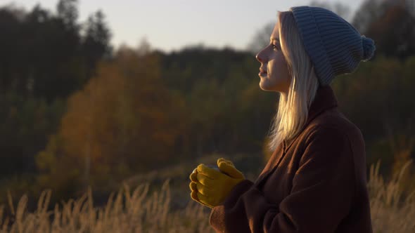 Beautiful girl with mug of tea in mountains Sudety in November in sunset alt