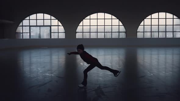 Little Girl Skater Glides on Skates on a Dark Ice Arena alt