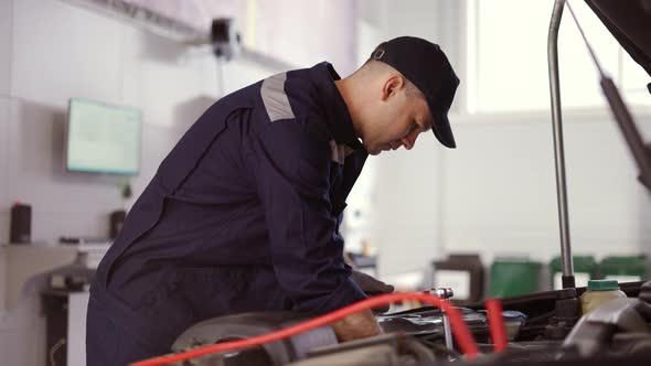 Car Mechanic Using Wrench to Repair the Engine in a Car Service alt