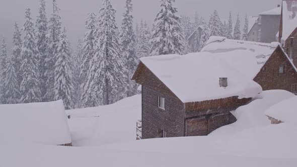 Camera Pan Over a Village in the Mountains Covered in Snow During a Heavy Snowfall alt