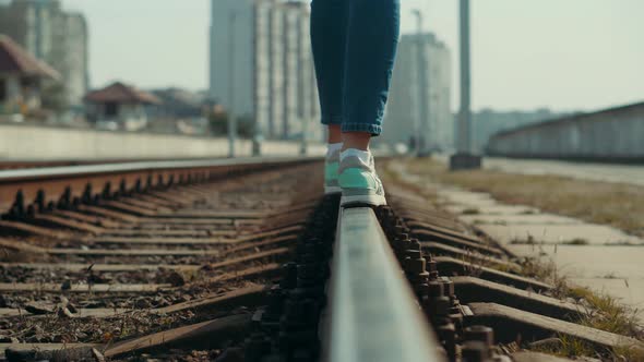 Woman Feet In Jeans Walking On Rail Road When Train Or Tram Cancelled. Legs Walking On Railway. alt