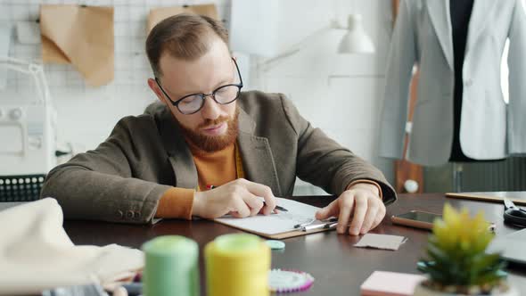 Tired Designer Drawing Clothes Sketch Then Falling Asleep on Work Table in Studio alt
