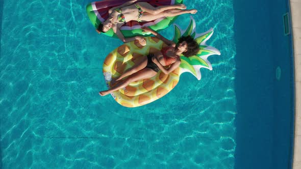 Drone Shot of Relaxed Women on Floaties in Pool alt
