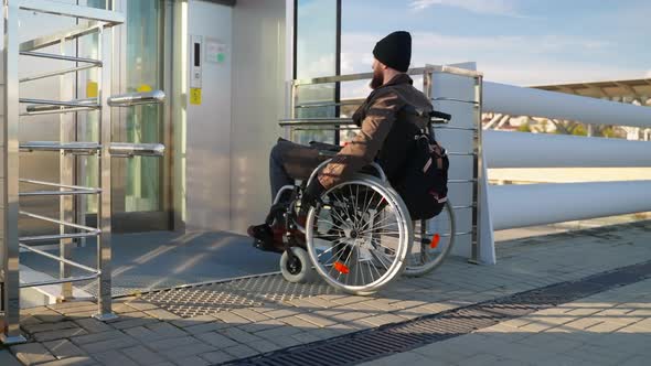 Paraplegic Man in Manual Wheelchair is Using Lift for Disabled People in City alt