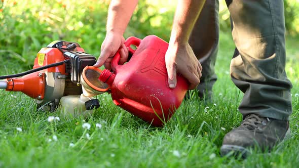 Gardener Refueling Brush Cutter Close Up. Gardening Tools Maintenance. Lawn Care with Brush Cutters. alt