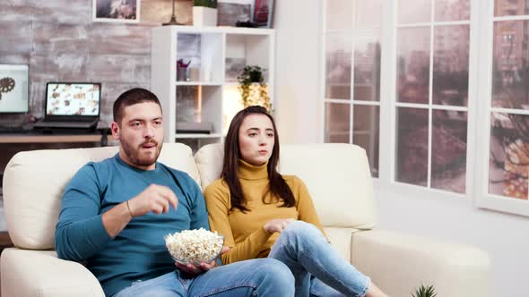 Young Couple Smiling While Watching Tv Sitting on Sofa alt