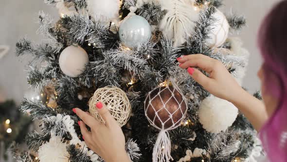 Young Woman Is Decorating Christmas Tree with Balls, Garlands and Pompons.