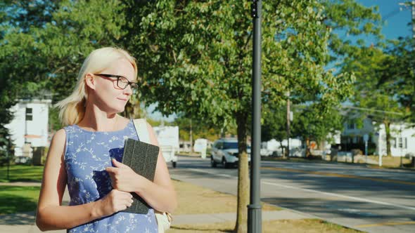 A Woman Walks Leisurely Along the Street of a Small Suburban City in the United States alt